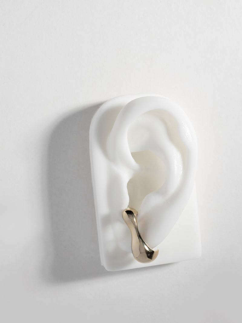 Close up product image of FARIS REST Stud in gold-plated bronze, shown on white silicon ear display (front view)