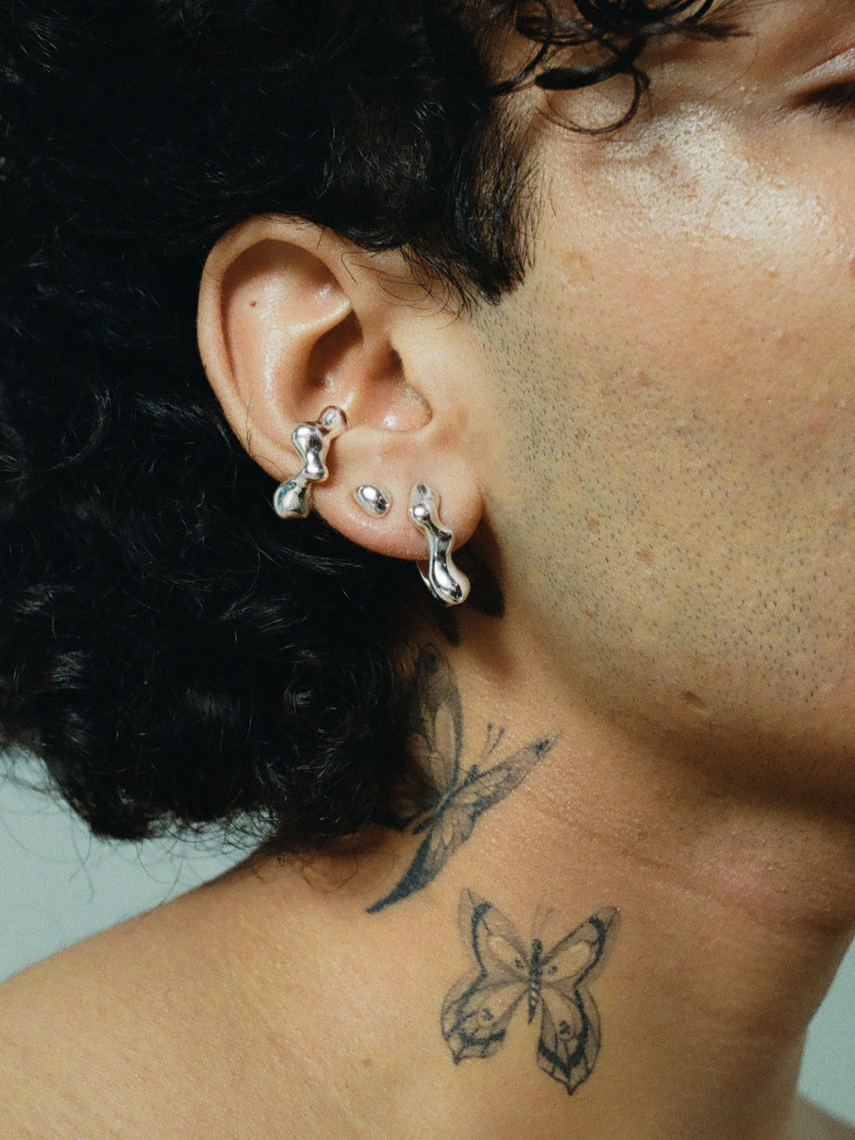FARIS EGG GEM Stud in Sterling Silver with topaz shown on male model with butterfly tattoos on neck. Styled with SEEP Ear Cuff in Sterling Silver and SEEP Hoop Small in Sterling Silver.