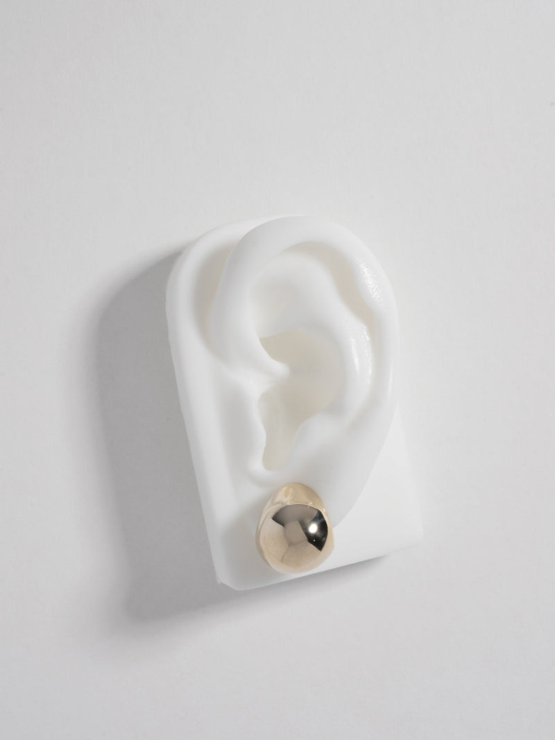 Product image of FARIS SUMO Stud in 14k gold-plated bronze, shown on white silicon ear display (front view)