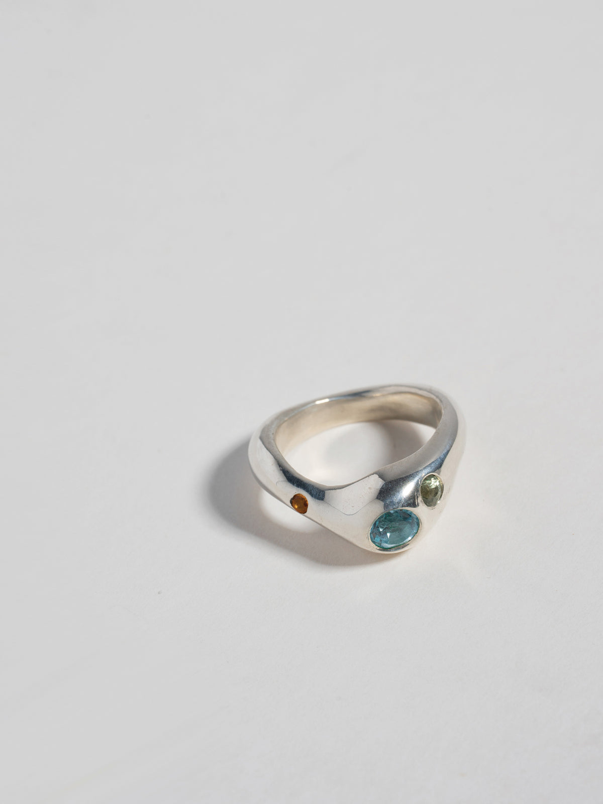 Close up product image of FARIS BAE Ring in sterling silver (front view). Face embedded with 5mm round topaz, with 3mm green sapphire and 2.3mm orange sapphire off to the sides