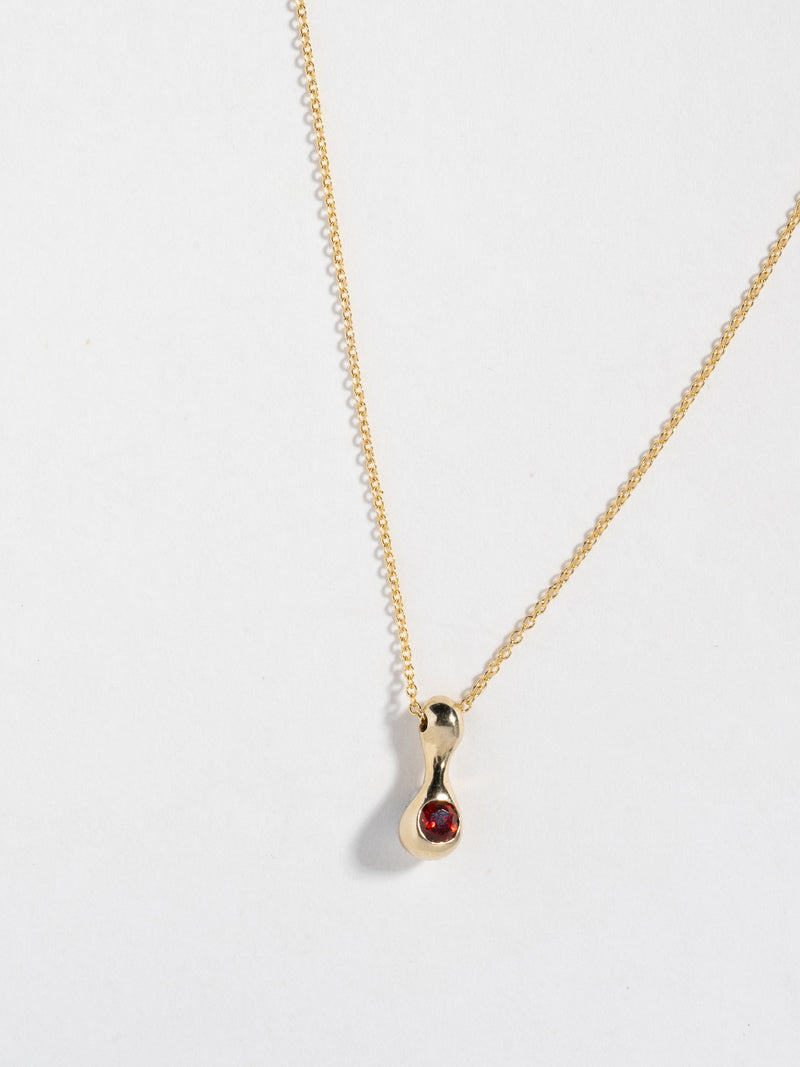 Close up image of FARIS BOLITO Necklace pendant in 14k gold with garnet (front view)
