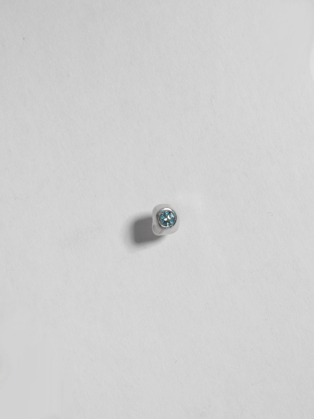 Close up product image of FARIS KIRA Stud in sterling silver with topaz, shown on white background (front view)