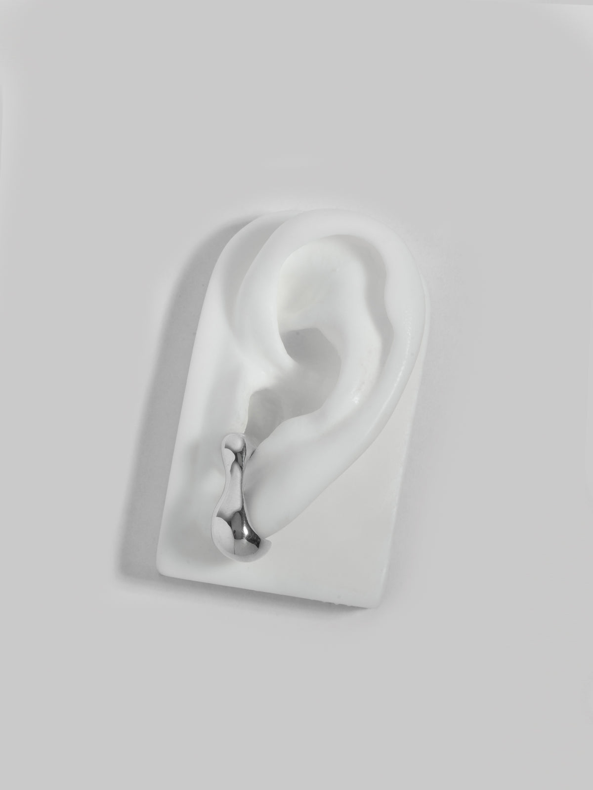 Product image of FARIS REST Stud in sterling silver, shown on white silicon ear display (front view)