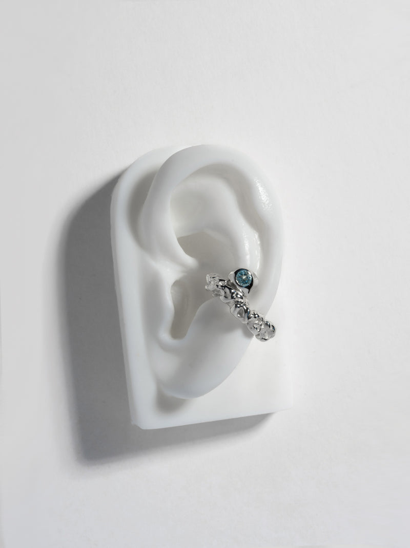 Product image of FARIS ROCA GEM Ear Cuff in sterling silver with topaz, shown on white, silicone ear display