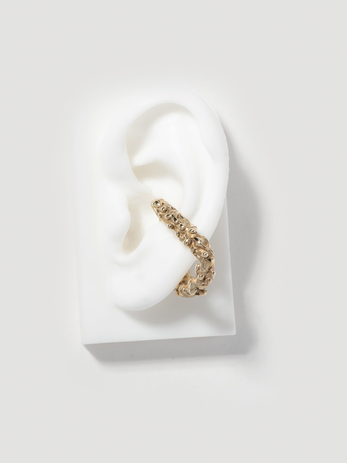 Product image of FARIS ROCA Hang (left ear orientation) in 14k gold plate. Shown on silicone ear. 