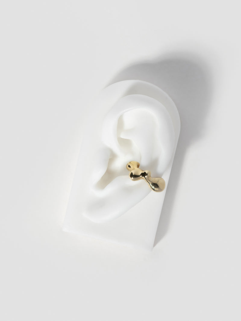 Product image of FARIS SEEP Ear Cuff in 14k gold plated bronze, shown on silicone ear