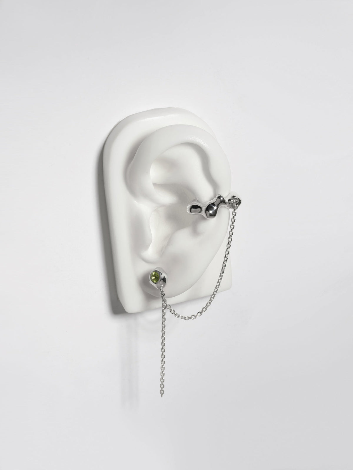 Product image of FARIS ZELDA Studcuff in sterling silver with peridot, shown on a white, silicon ear display