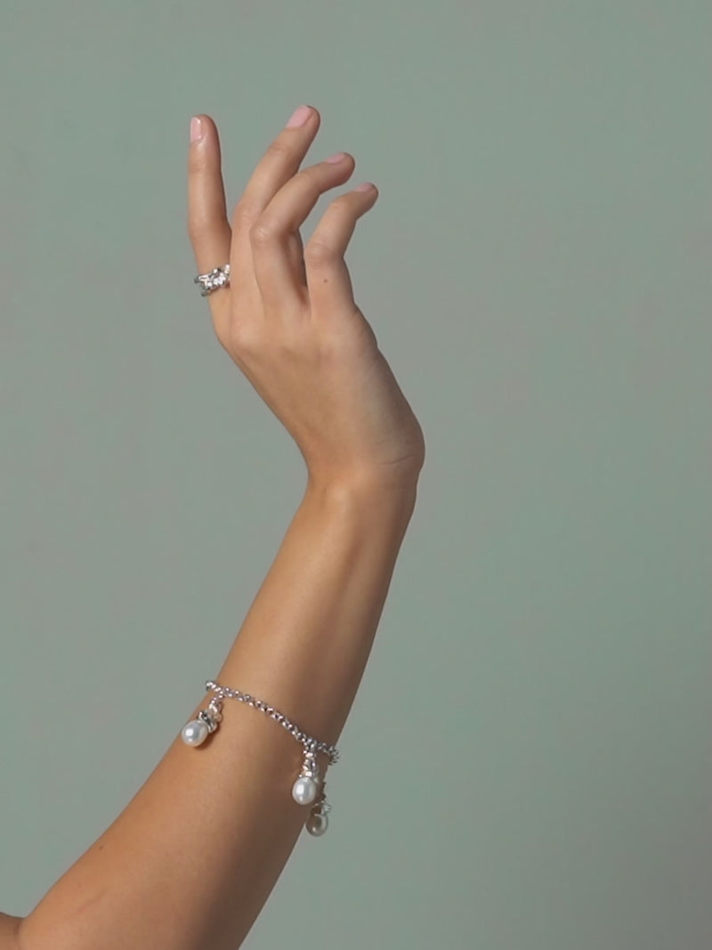 Short clip of FARIS LAVA Band 10mm in sterling silver shown on model. Hand moves to highlight the way light hits the bands textured surface. Styled with SOPHIA Charm Bracelet in sterling silver 