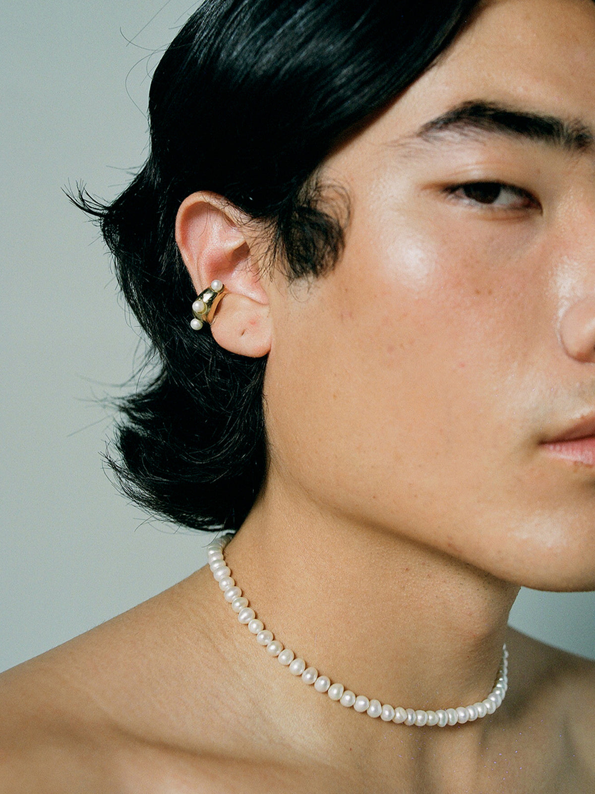 FARIS PATTA Collar in Gold-Plated bronze with white pearls shown on male model. Styled with GROSSO PERLA Ear Cuff in gold-plated bronze.
