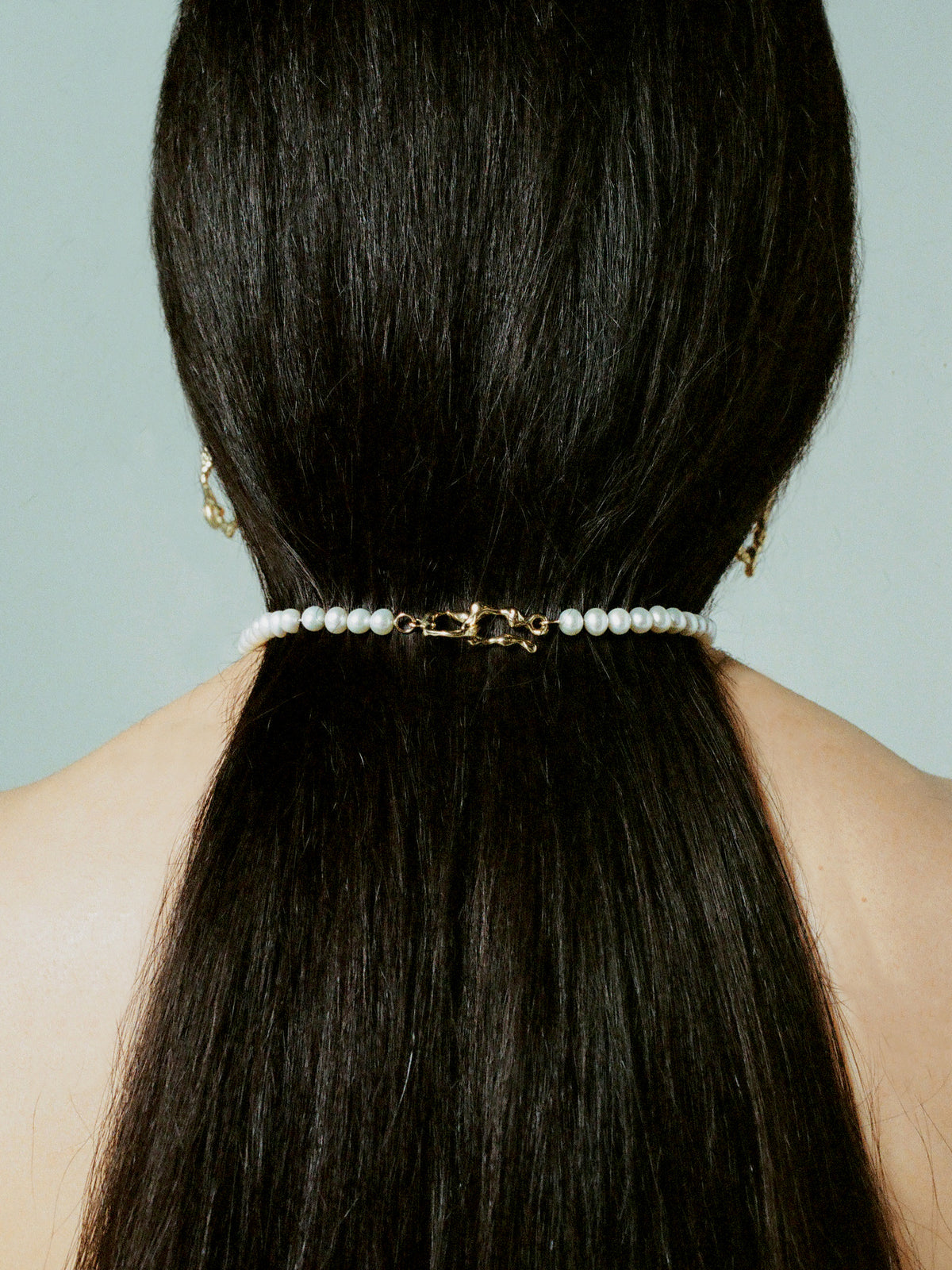 Hand-carved hook-eye closure on FARIS PATTA Collar in gold-plated bronze, shown on model. 