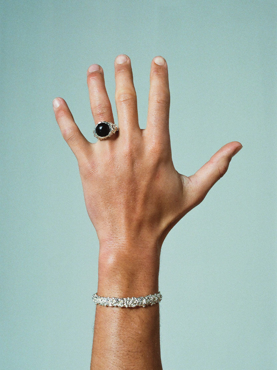 FARIS ROCA BAM Ring in sterling silver with onyx, shown on model. Styled with ROCA Cuff in sterling silver. Soft, teal blue background