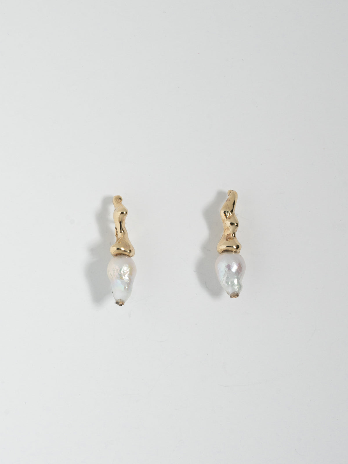 Product image of FARIS SPRIG PERLA Earrings in 14k gold with petite, white baroque pearls. Laid side by side, front view